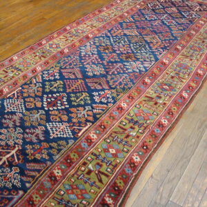 Long, dark blue geometric runner with detailed red and olive green borders rests on wood planks.