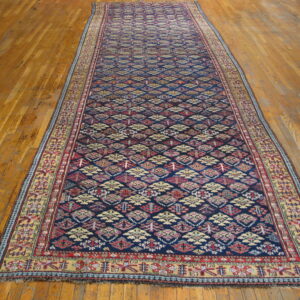 Dark blue runner rug featuring red, cream, and yellow diamond motifs on wooden flooring.