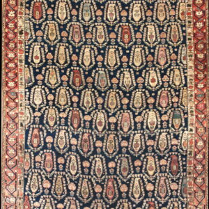 Dark blue rug with a repeating multi-colored boteh pattern and a layered red and cream border.