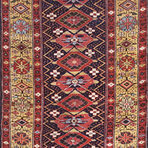 Long, narrow geometric runner rug in dark blue, red, and gold colors with detailed borders.