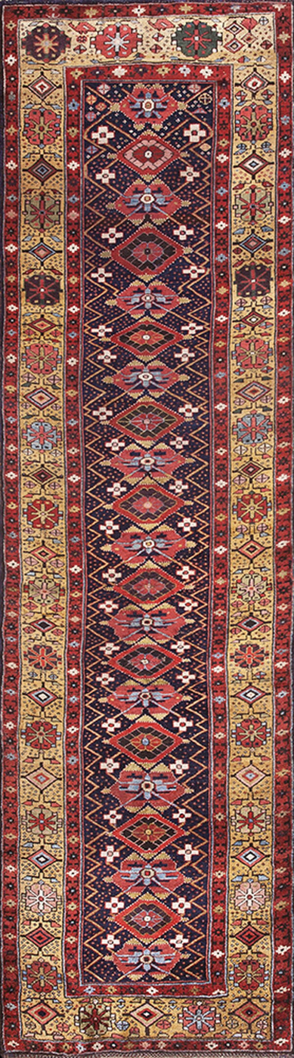 Long, narrow geometric runner rug in dark blue, red, and gold colors with detailed borders.