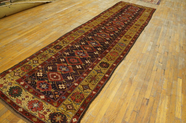 Detailed runner rug in dark red, navy, and gold tribal patterns on wide plank wood flooring.
