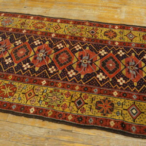 Geometric runner rug in rust, navy, and gold sits on light, rustic wood planks.