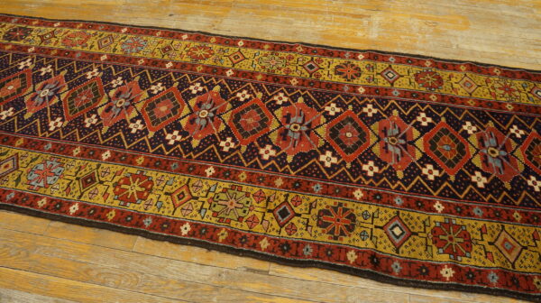 Geometric runner rug in rust, navy, and gold sits on light, rustic wood planks.