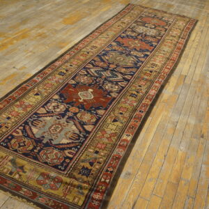 Navy blue and terracotta geometric runner rug displayed diagonally on worn wooden planks.