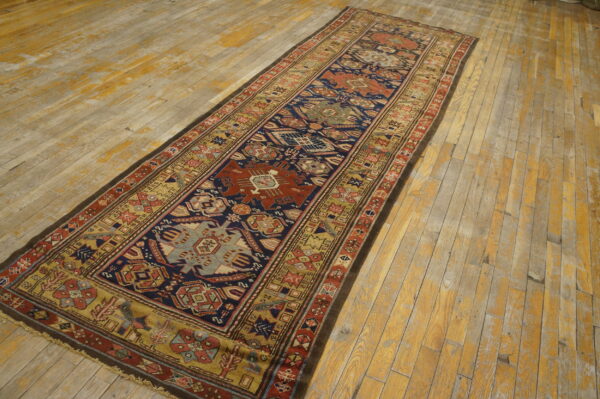 Navy blue and terracotta geometric runner rug displayed diagonally on worn wooden planks.