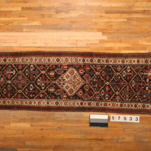 Geometric navy and red runner rug with a cream medallion displayed on a light wooden floor.