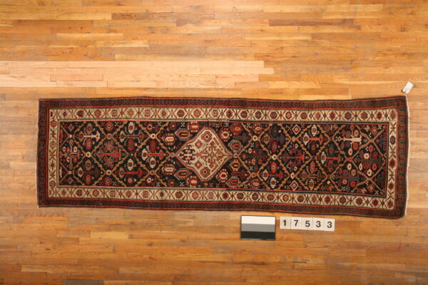 Geometric navy and red runner rug with a cream medallion displayed on a light wooden floor.
