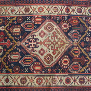 Navy blue rug with a central cream diamond medallion and geometric red and gold tribal patterns.