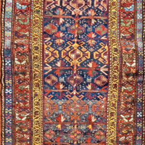 Low-pile runner rug showing a dark blue center field and vibrant red, gold, and multicolored geometric patterns.