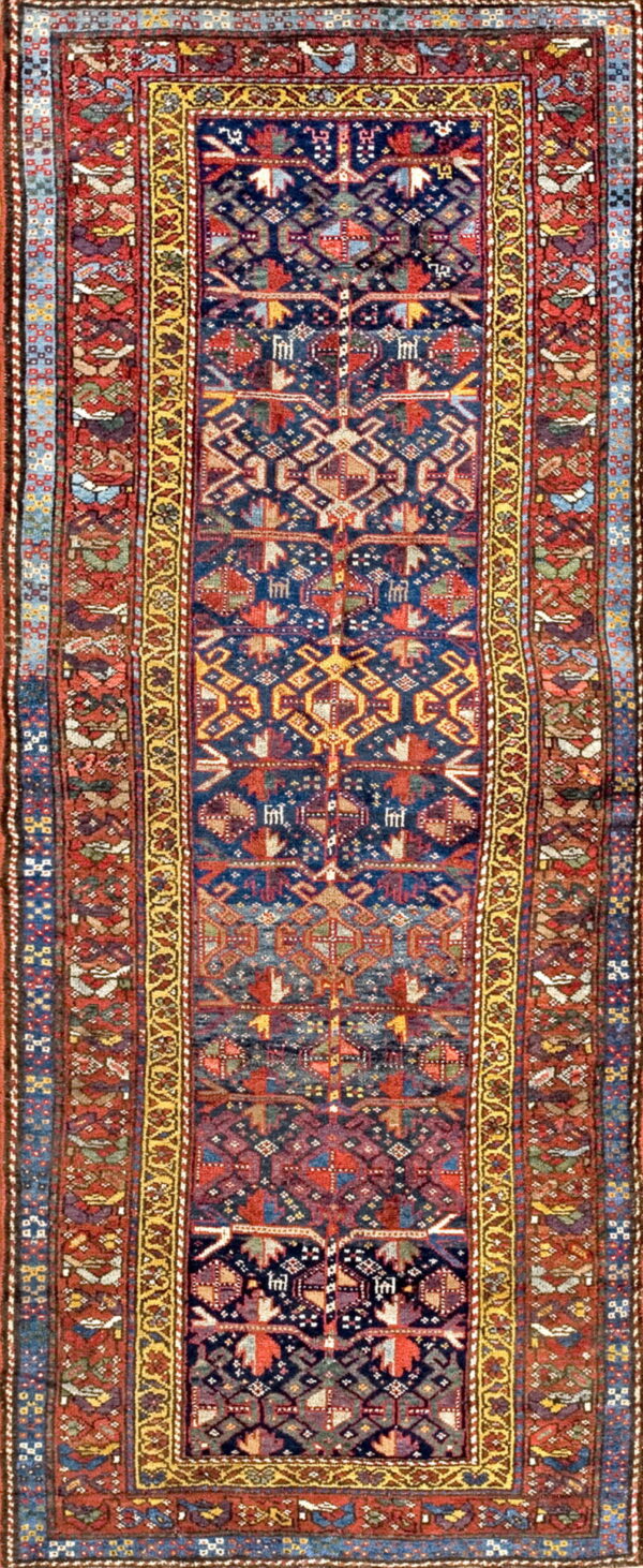 Low-pile runner rug showing a dark blue center field and vibrant red, gold, and multicolored geometric patterns.