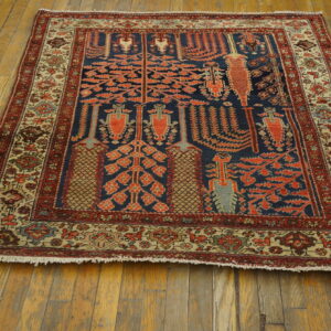 Blue rug with stylized orange botanical designs and intricate beige borders on distressed wood floorboards.