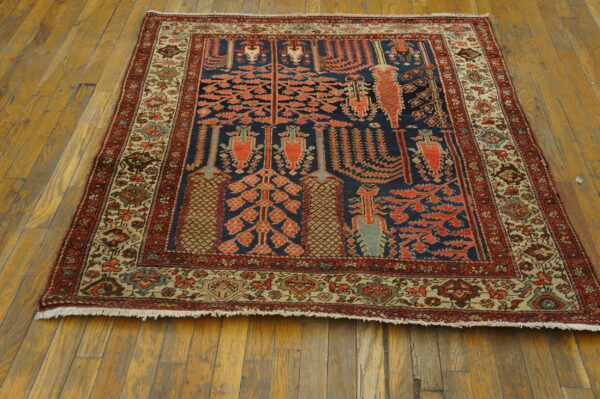 Blue rug with stylized orange botanical designs and intricate beige borders on distressed wood floorboards.