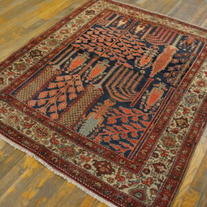 Geometric rug featuring navy and salmon red motifs, bordered in beige and red, resting on light wood floors.
