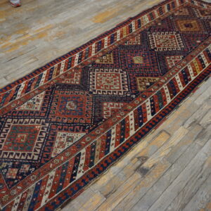 Tribal runner rug in rust and navy with geometric diamonds on distressed gray wood planks.