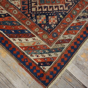 Red, navy, and cream geometric pattern rug corner visible against weathered gray wood flooring.