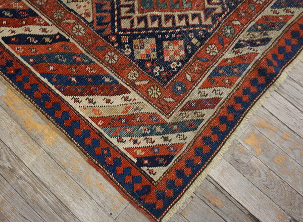 Red, navy, and cream geometric pattern rug corner visible against weathered gray wood flooring.