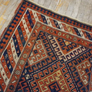 Geometric tribal rug in rust, navy, and cream colors on light, rustic wood planks.