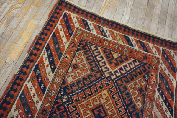 Geometric tribal rug in rust, navy, and cream colors on light, rustic wood planks.