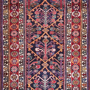 Traditional runner rug featuring a dense navy geometric field bordered by complex red and ivory patterns.