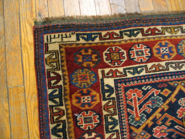 Geometric patterned rug corner in red, navy, and cream, showing short pile on plank hardwood.