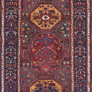 A long runner rug featuring a deep red field with stacked geometric medallions and a navy blue border.