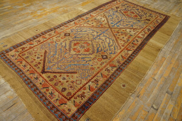 Rare collectable tribal camel color late 19th century antique nw persian serab rug 5 Tan, rust, and blue patterned rug with wide flatwoven borders displayed on worn wood flooring.