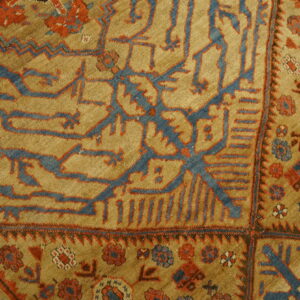 Geometric blue and red tribal patterns cover a textured golden tan rug field.