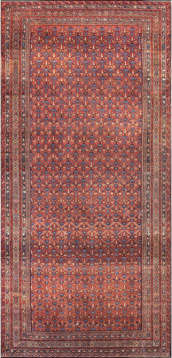 Full view of a dense red runner rug with blue repeating geometric motifs and striped borders.