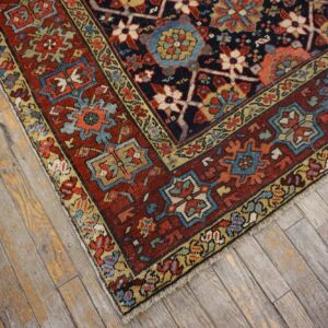 A patterned rug in navy, red, and blue with geometric motifs rests on distressed wood floorboards.