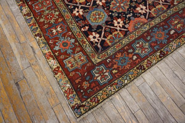 A patterned rug in navy, red, and blue with geometric motifs rests on distressed wood floorboards.