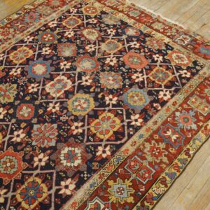 Navy field rug with complex red, yellow, and light blue geometric floral motifs on rustic wooden floorboards.