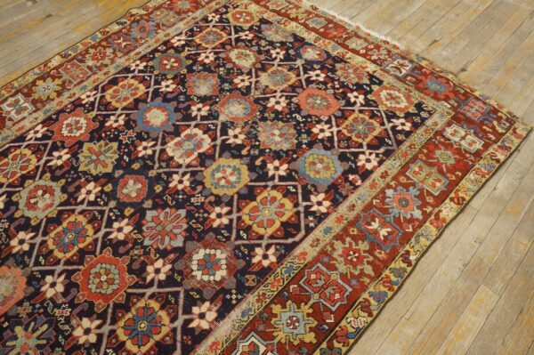 Navy field rug with complex red, yellow, and light blue geometric floral motifs on rustic wooden floorboards.