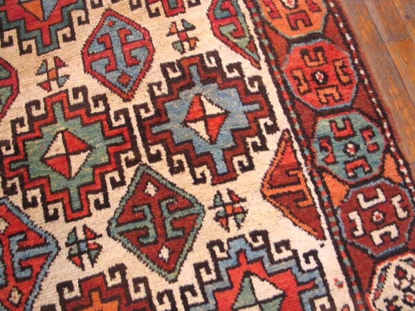 A close-up shows complex geometric patterns in cream, red, blue, and green on hardwood flooring.