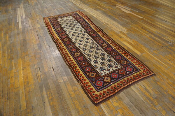 Geometric runner rug with cream, red, and gold patterns rests on distressed wooden floorboards.