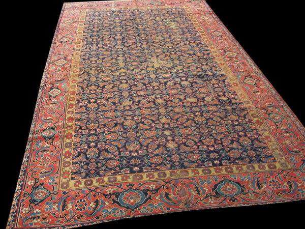 Detailed blue and rust rug with an overall repeating floral pattern against a solid black background.