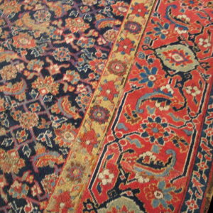 Traditional rug detail showing a dense navy blue field next to a floral red and gold border.