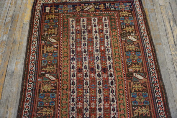 Geometric rug with a vertically striped center and tribal motifs in red, navy, and brown on distressed wood floorboards.