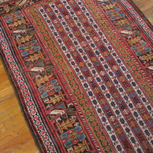 Low-pile runner rug featuring geometric tribal patterns in red, blue, gold, and dark brown rests on hardwood flooring.