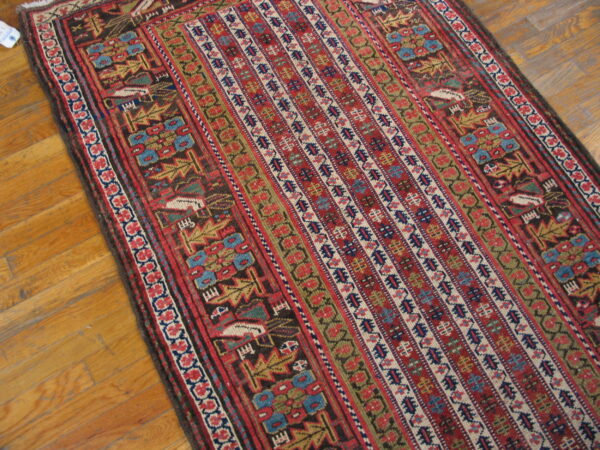 Low-pile runner rug featuring geometric tribal patterns in red, blue, gold, and dark brown rests on hardwood flooring.