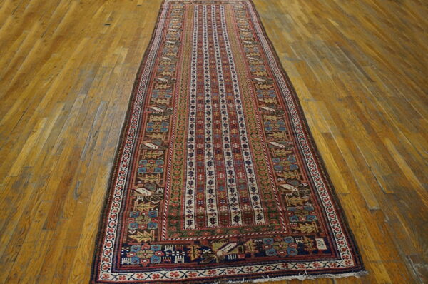 Red, blue, and brown low-pile runner rug with complex tribal patterns on plank hardwood flooring.