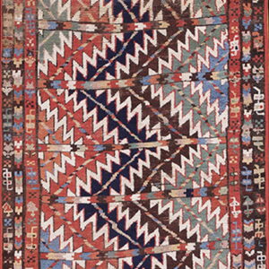 Low-pile rug featuring bold diagonal zigzag patterns in red, navy, brown, teal, and white.