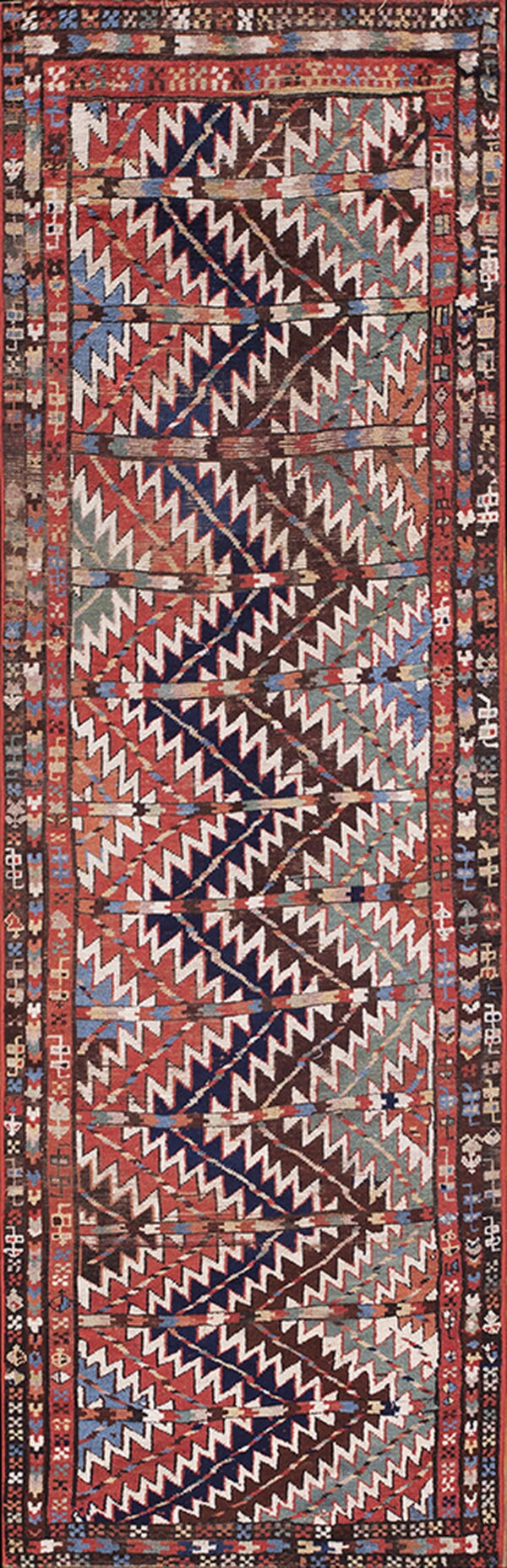 Low-pile rug featuring bold diagonal zigzag patterns in red, navy, brown, teal, and white.