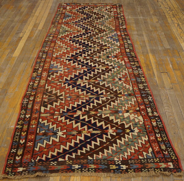 Geometric runner rug with alternating wide bands of multicolored zigzags on distressed wooden planks.