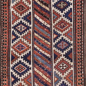 Geometric runner rug featuring blue, rust, cream, and black colors in a complex striped and diamond design.