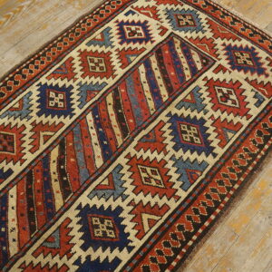 Geometric runner rug featuring red, blue, and cream zigzag designs on distressed light wood plank flooring.
