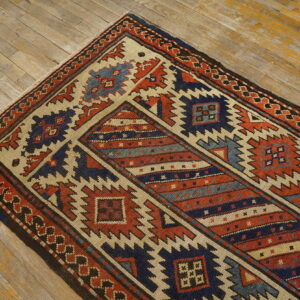 Flatweave runner in terracotta, navy, and beige with sharp geometric patterns on worn wood floorboards.