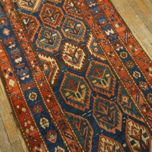 Geometric runner rug in navy blue, rust, and beige on rustic wood plank flooring.