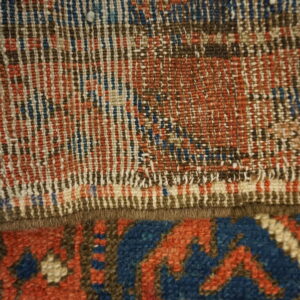 Close-up of blue, red, and brown woven fibers transitioning from flat texture to a dense geometric pile.