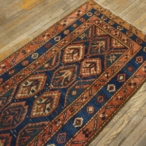 Blue and rust geometric runner rug with a repeating pattern on rustic wooden plank flooring.